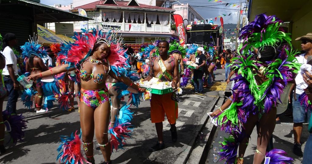 People dancing and eating at a colorful Dominica village festival with music and food stalls