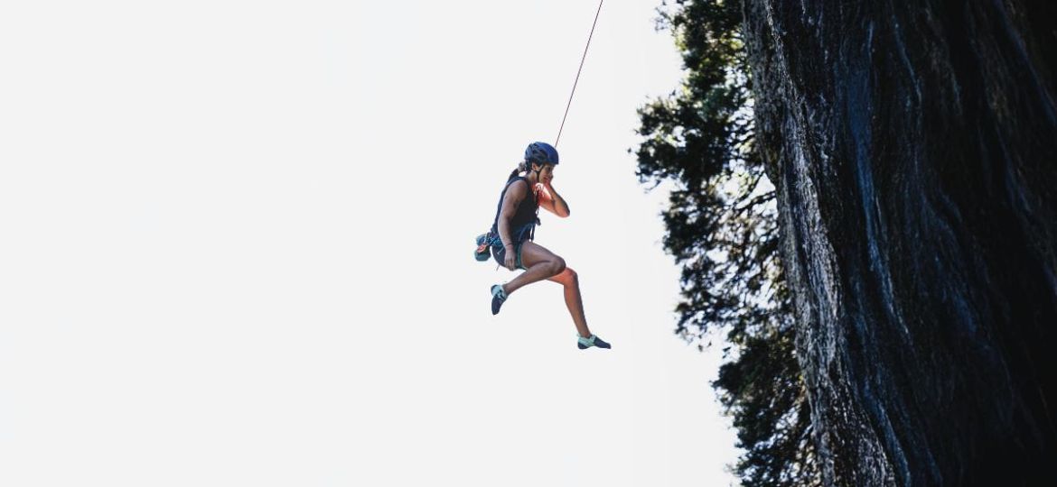 Person rappelling down waterfall in Dominica canyon